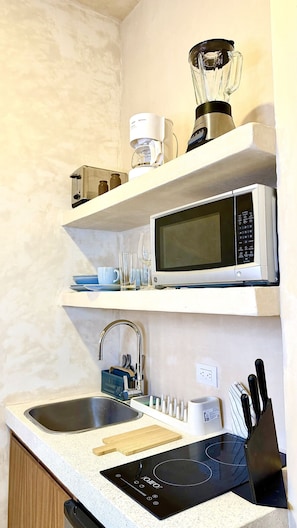 Eine Küche mit Mikrowelle, Kaffeemaschine, Mixer und Spüle mit Besteck.