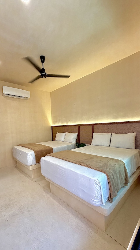 Ein Hotelzimmer mit zwei Betten, einem Deckenventilator und einer Klimaanlage.