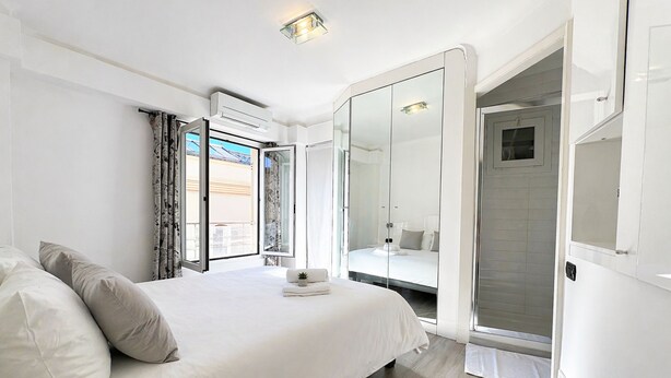 A bedroom with a bed, a walk-in closet, and a bathroom with a shower. - Joli 2 pi ces Monaco (Monaco)