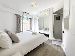 A bedroom with a bed, a walk-in closet, and a bathroom with a shower.