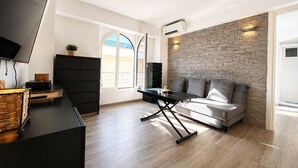 A modern living room with a sofa, a TV, a fireplace, and a stone wall. - Joli 2 pi ces Monaco (Monaco)