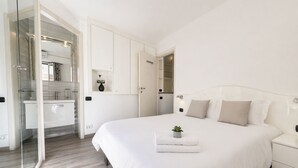 A bedroom with a large bed, a bedside table, a nightstand, a small potted plant, and a walk-in closet. - Joli 2 pi ces Monaco (Monaco)