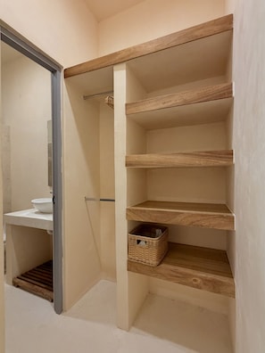 Ein begehbarer Kleiderschrank mit Holzböden und einem Korbwäschesammler.