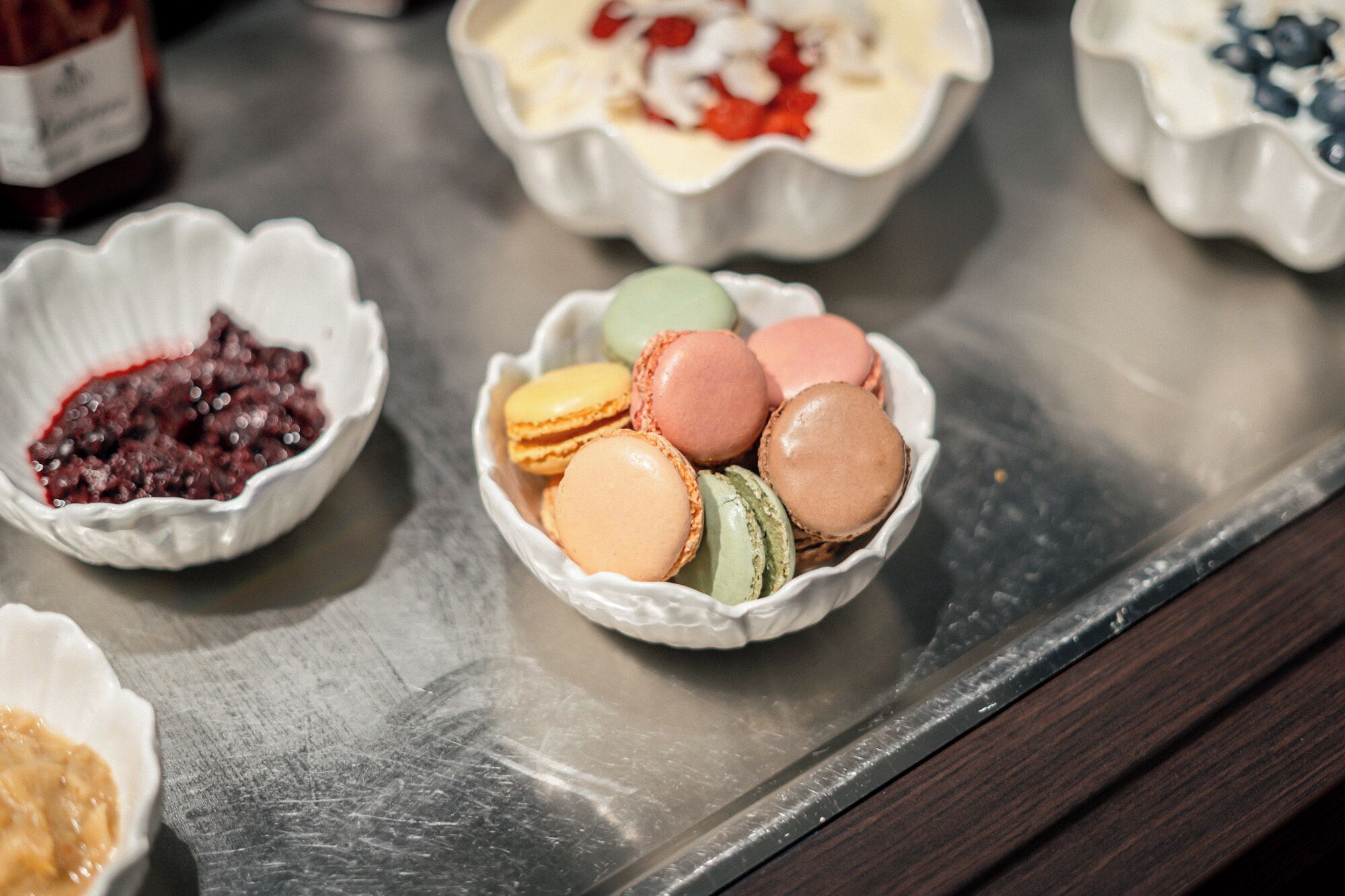 A tray with various food items including macarons and a dessert with red fruit.