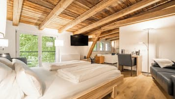 Quarto com teto de madeira, uma cama, escrivaninha, cadeira e televisão.
