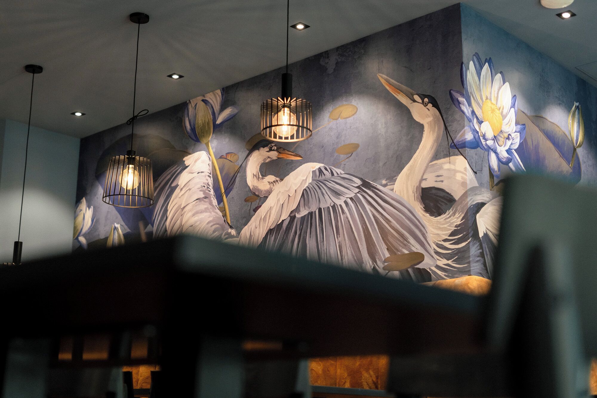 A mural with birds and flowers, hanging lights, and a partially visible seating area.