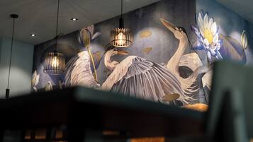 A mural with birds and flowers, hanging lights, and a partially visible seating area.