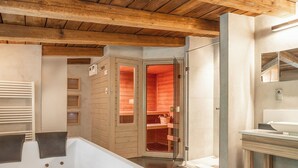 Un interior moderno con techo de madera, una bañera blanca y una sauna con paredes de vidrio.