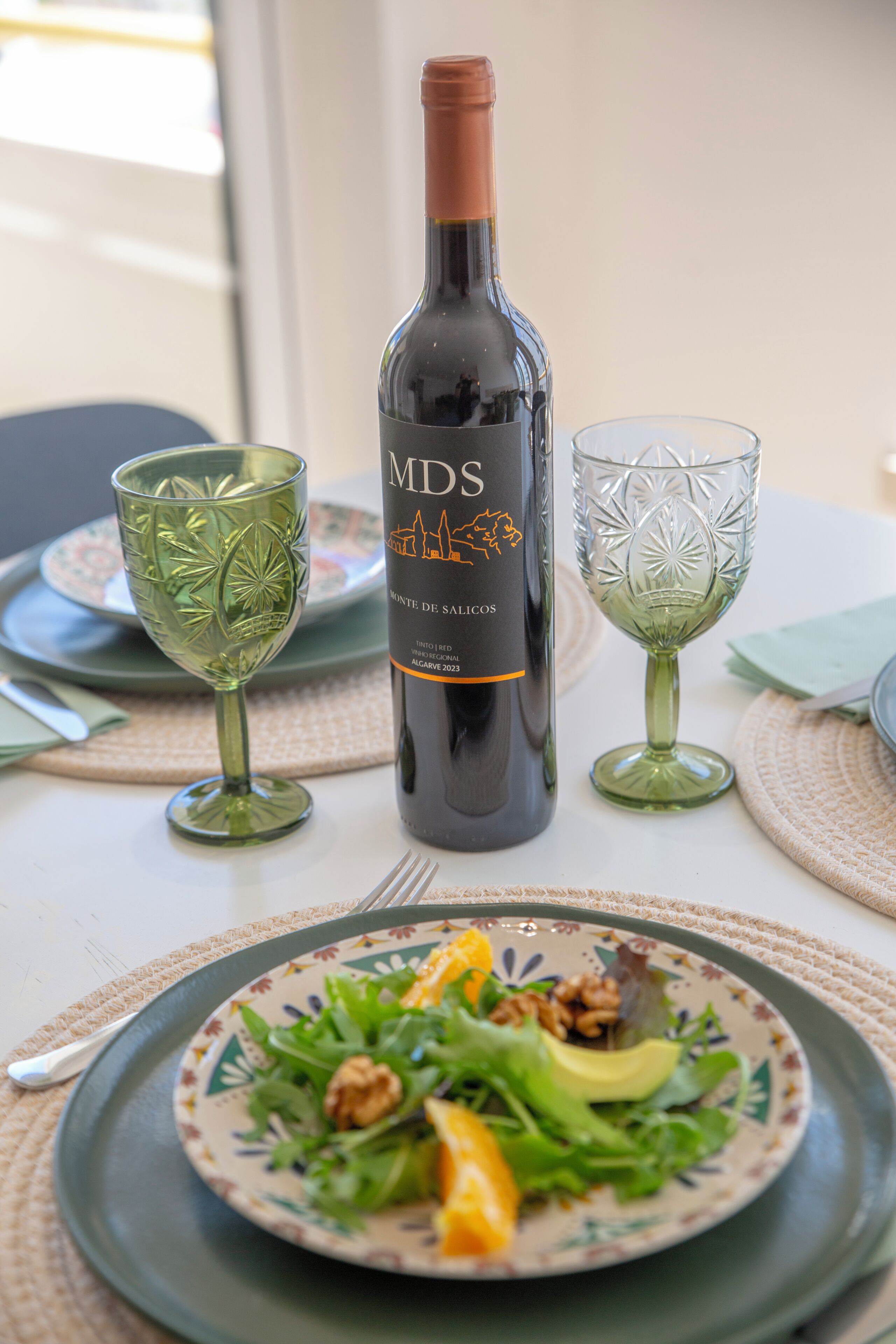 Een fles wijn, twee glazen en een bord met eten op een tafel.