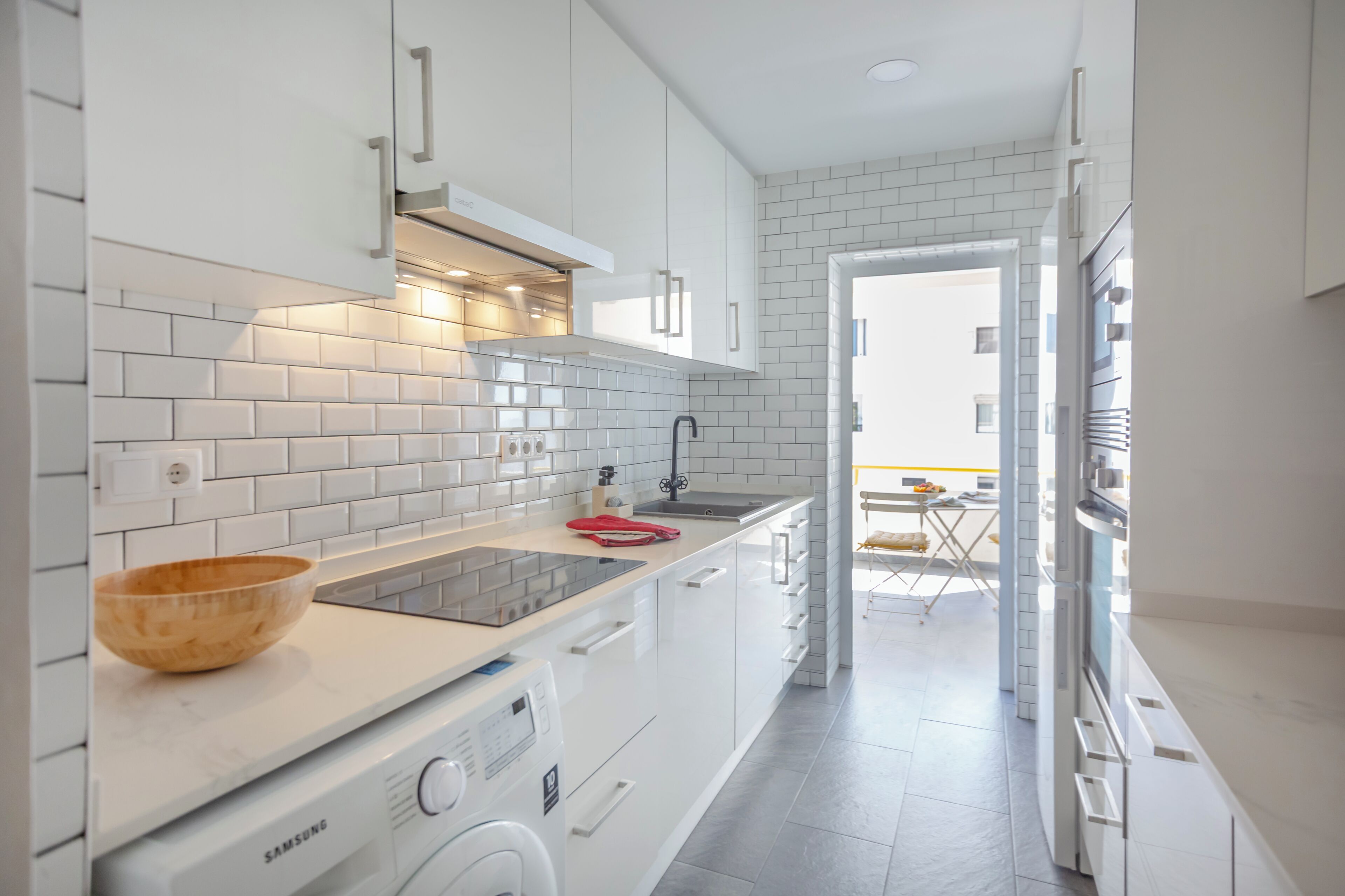 Een moderne keuken met witte kastjes, een inbouwoven en een roestvrijstalen spoelbak.
