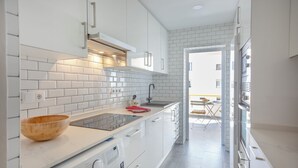 A modern kitchen with white cabinetry, a built-in oven, and a stainless steel sink.