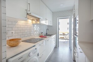 Eine moderne Küche mit weißen Schränken, einem eingebauten Ofen und einer Edelstahl-Spüle.