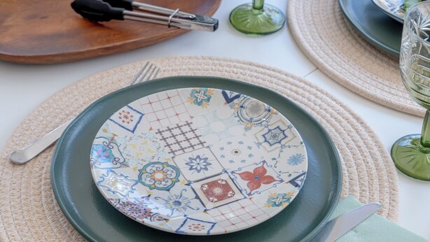 A table set with plates, cutlery, and a bowl of fruit.