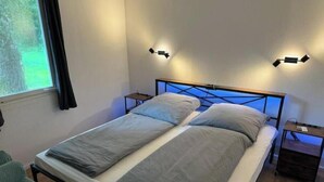 A double bed with a metal frame, two bedside tables, and wall-mounted lighting. - Vacation village Seddiner See - Bungalow 2 (Seddiner See)