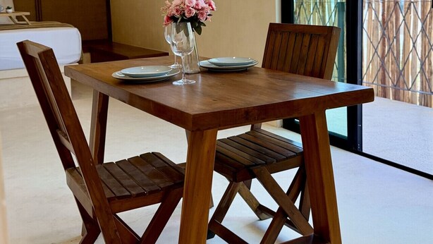 Een eetgedeelte met een houten tafel, stoelen en een bloevas.