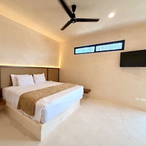 Ein modernes Schlafzimmer mit Bett, Deckenventilator, Wand-Fernseher und einem großen Fenster.