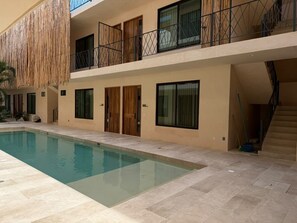 Ein modernes Gebäude mit Schwimmbad, Balkonen und einer Treppe.