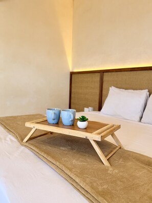 Ein Bett mit einem Holftablett, das zwei Tassen und eine kleine Pflanze trägt.
