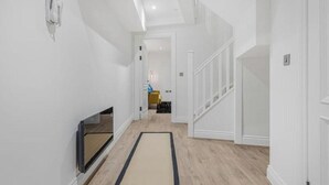 Ein moderner Flur mit Flachbildfernseher, Holzboden und einer Treppe.
