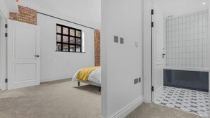 Ein Schlafzimmer mit Bett, Fenster, Tür und einem Badezimmer mit Fliesenboden.