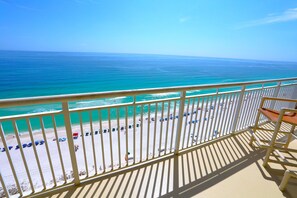 Ein Balkon mit Blick auf einen Strand, einem Geländer und einem Stuhl.