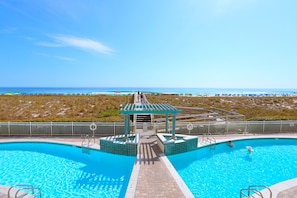 Ein Pool mit Blick auf den Strand, ein überdachter Bereich und ein eingezäunter Weg.