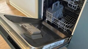An open dishwasher with a control panel and a stainless steel interior.