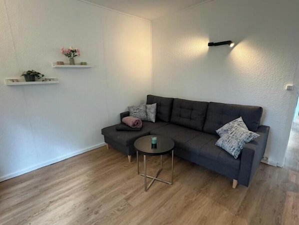 Un salon moderne avec un canapé gris, une petite table ronde et un plancher en bois.
