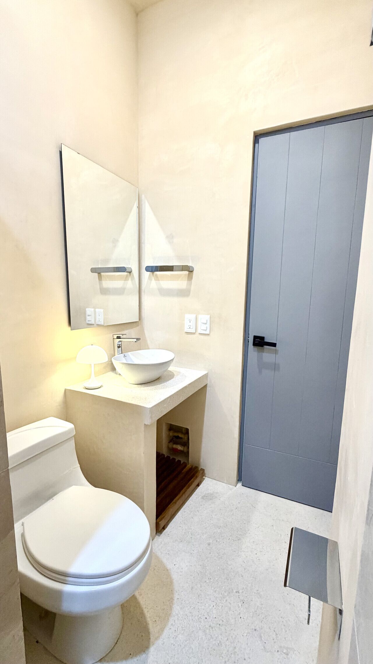 Une salle de bain comprenant des toilettes, un lavabo, un miroir et une porte.
