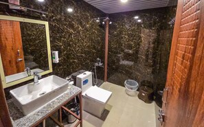 Une salle de bain avec un mur en marbre, un lavabo, un miroir et une douche.