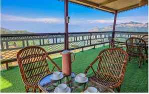 Un espace extérieur aménagé avec des meubles de jardin en osier, comprenant des chaises et une table, et offrant une vue sur un paysage pittoresque.