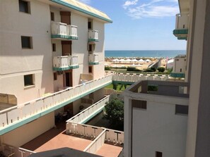 Ein mehrstöckiges Hotel mit Balkonen, einem Poolbereich und Blick auf den Strand.