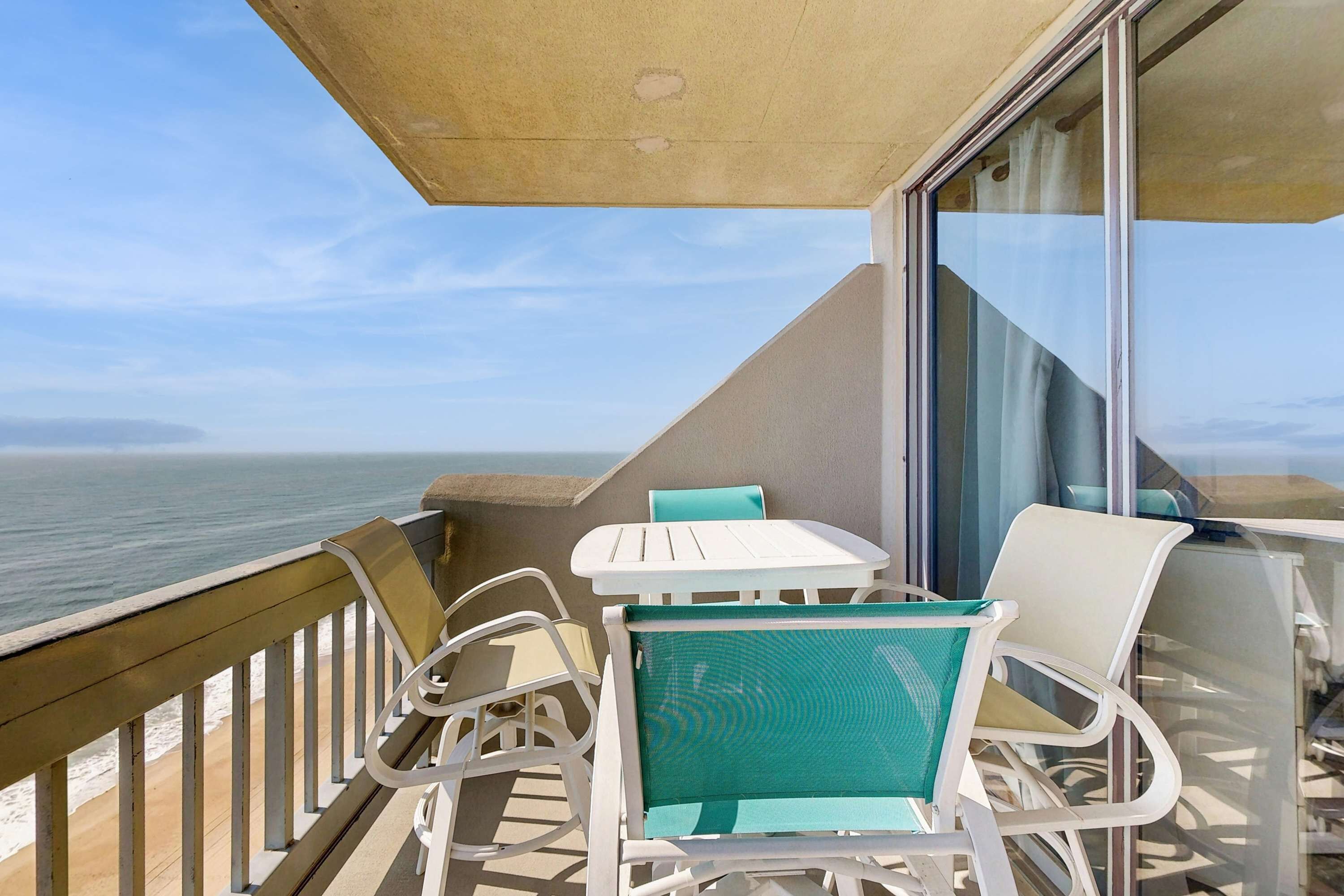 Ein Balkon mit Tisch und Stühlen mit Blick auf den Ozean.