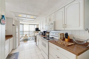 Eine moderne Küche mit weißen Schränken, einer Granit Arbeitsplatte und Blick zum Balkon.