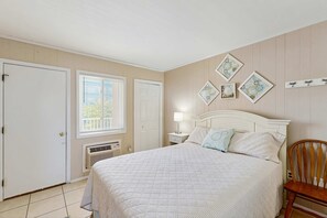 Ein Schlafzimmer mit Bett, Sessel, Nachttisch, Lampe und Wanddekorationen.