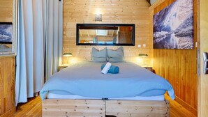Una habitación con paneles de madera, una cama, un espejo y un cuadro en la pared.