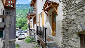 Un carrer estret amb un edifici de pedra, balcons de fusta i un cotxe estacionat.
