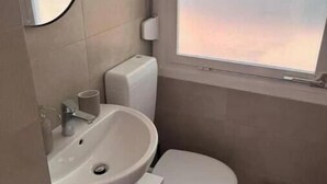A small bathroom with a toilet, sink, and a window. - Vacation village Seddiner See - Bungalow 4 (Seddiner See)
