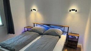 A single bed with a metal frame, two bedside tables, and wall-mounted lights. - Vacation village Seddiner See - Bungalow 4 (Seddiner See)
