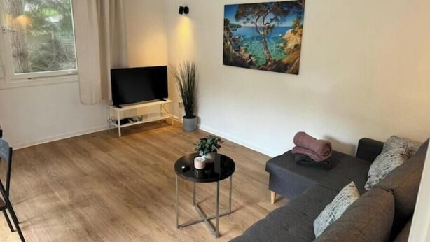 A living room with a TV, a painting, a sofa, and a coffee table. - Vacation village Seddiner See - Bungalow 4 (Seddiner See)