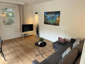 A living room with a TV, a painting, a sofa, and a coffee table.