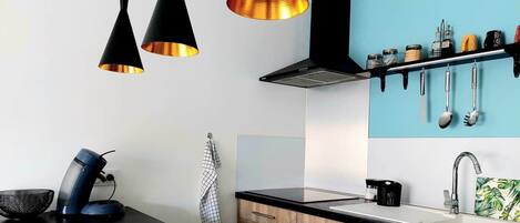 A modern kitchen with pendant lights, a coffee machine, and a hanging utensil rack.