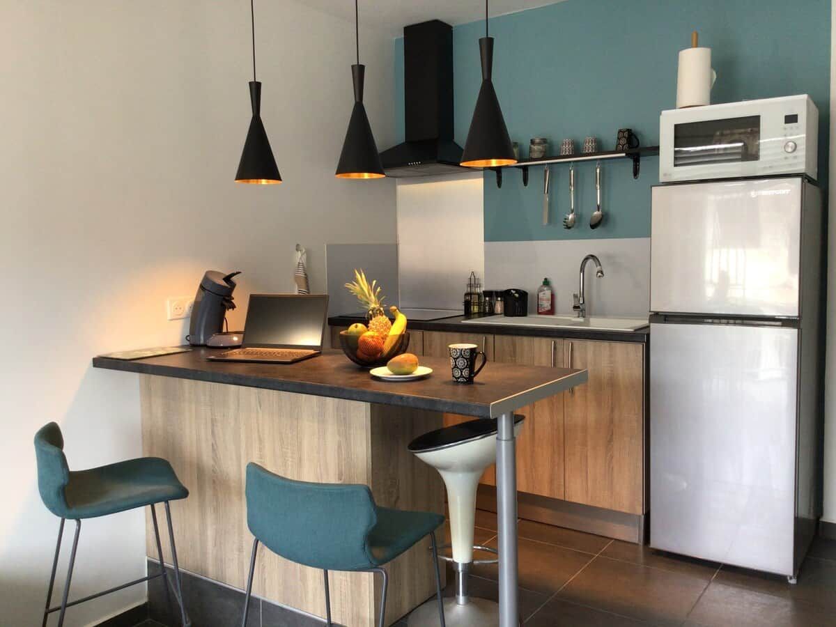 A modern kitchen with a central island, bar stools, a microwave, and a refrigerator.