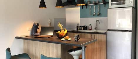 A modern kitchen with a central island, bar stools, a microwave, and a refrigerator.
