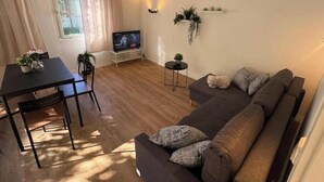 A living room with a sofa, a TV, a dining table, and chairs. - Vacation village Seddiner See - Bungalow 5 (Seddiner See)