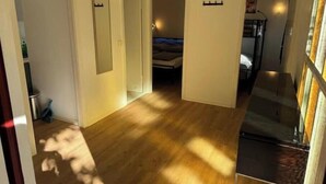 A hallway with wooden flooring, a bed in the background, and a staircase to the right. - Vacation village Seddiner See - Bungalow 5 (Seddiner See)