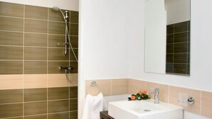 Un baño moderno con ducha, lavabo y espejo.