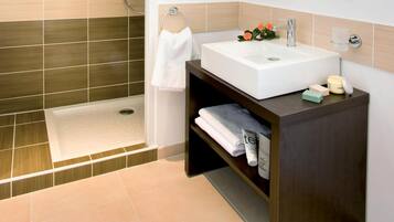 A modern bathroom with a rectangular sink, a shower, and a towel rack.