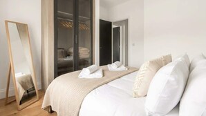 Una camera da letto con un letto, un armadio, uno specchio e una porta che conduce a un'altra stanza.