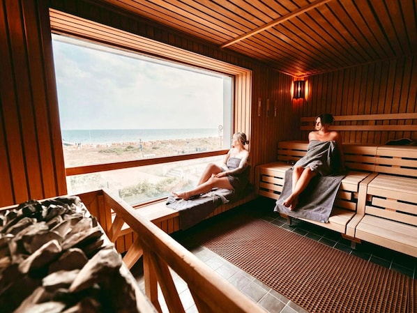 Eine Sauna mit Holzbänken und einem großen Fenster mit Blick auf einen Strand.